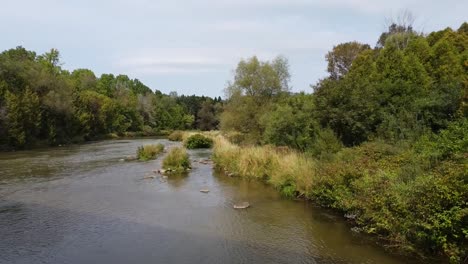 Toma-Aérea-Hacia-Atrás-Sobre-El-Idílico-Río-Ontario-Debajo-Del-Puente-En-El-Desierto-De-Canadá