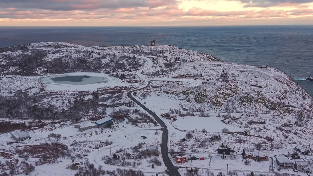 En vidstrakt utsikt fra Signal Hill med utsikt over snødekte åser og Atlanterhavet under en pastellfarget himmel
