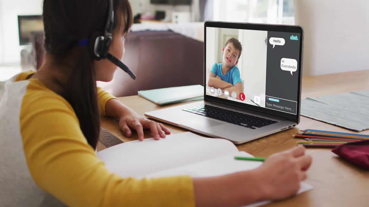 Schoolgirl using laptop for online lesson at home, with school friend and web chat on screen