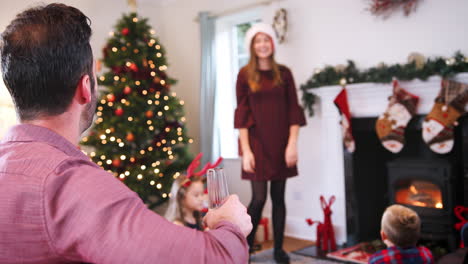 adolescente actuando como mímica como familia de varias generaciones jugando al juego de charadas navideñas en casa juntos