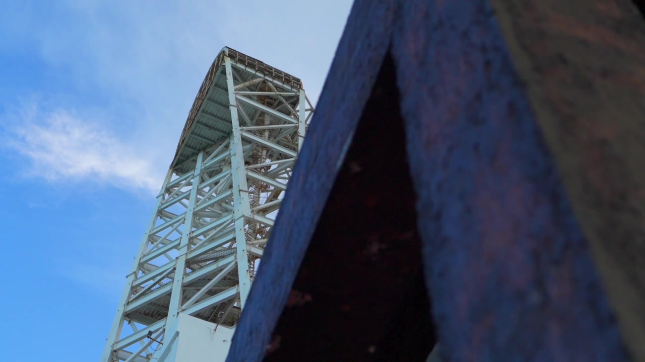 Un'inquadratura dinamica in tilt-down che mostra l'imponente edificio Mega Escultura a Chetumal in un pomeriggio sereno con un cielo azzurro brillante.