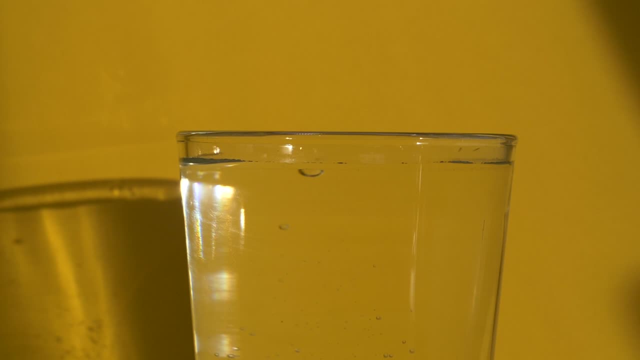 slowmotion 맑은 물 유리에 태블릿을 떨어 뜨리는 남성 손의 클로즈업
