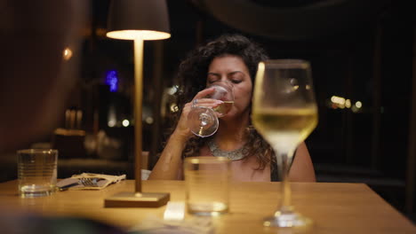 woman having an elegant dinner at the beach resort and drinking wine