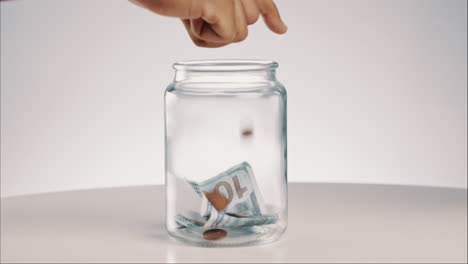 glass, jar and hand with money