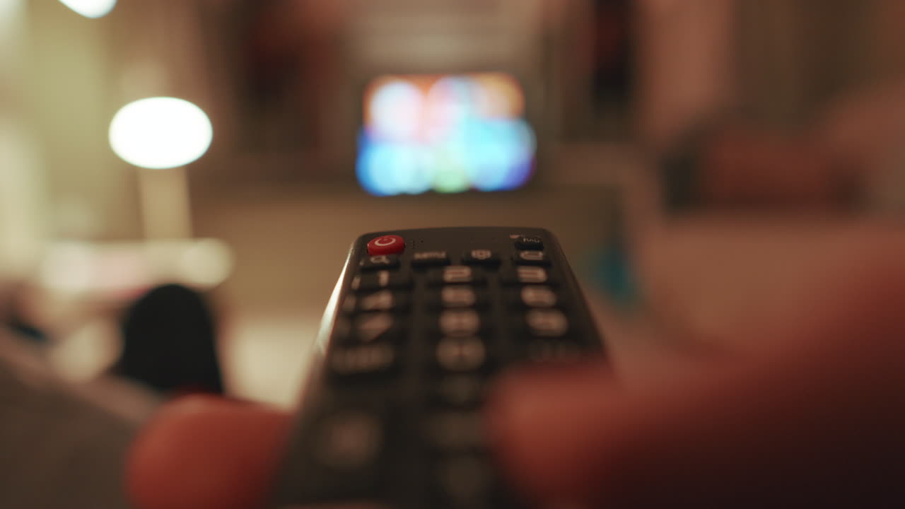 Telecomando in mano puntato verso una TV, a indicare il tempo libero
