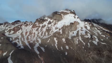 a breathtaking aerial dolly-in shot of carihuairazo volcano in ecuador, partially covered in snow. the rugged volcanic landscape is revealed as the drone moves closer, capturing its majestic peaks.
