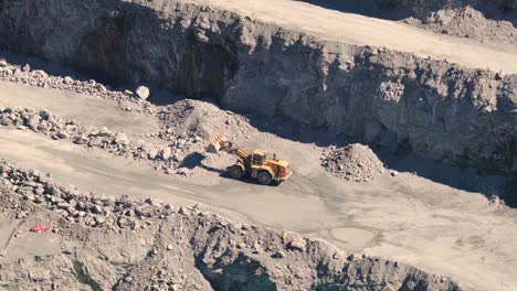 drone footage captures a quarry with trucks and excavators in action, highlighting industrial mining operations under natural daylight
