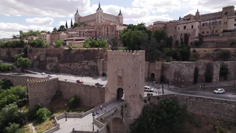 Aerial:-Puente-de-Alcántara-spanning-Toledo's-river,-overlooked-by-Alcázar-of-Toledo