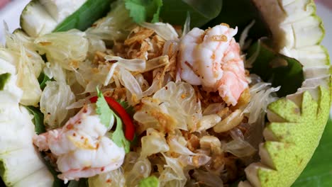 a vibrant thai pomelo salad featuring shrimp, herbs, and spices, beautifully presented in a carved pomelo bowl