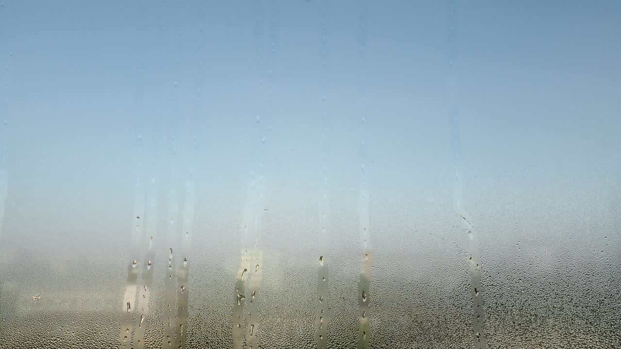 Glass with condensate or steam after heavy rain. Wet window, condensation on window glass