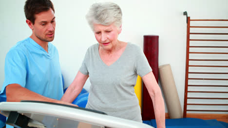 Physical-therapist-showing-patient-how-to-use-exercise-machine