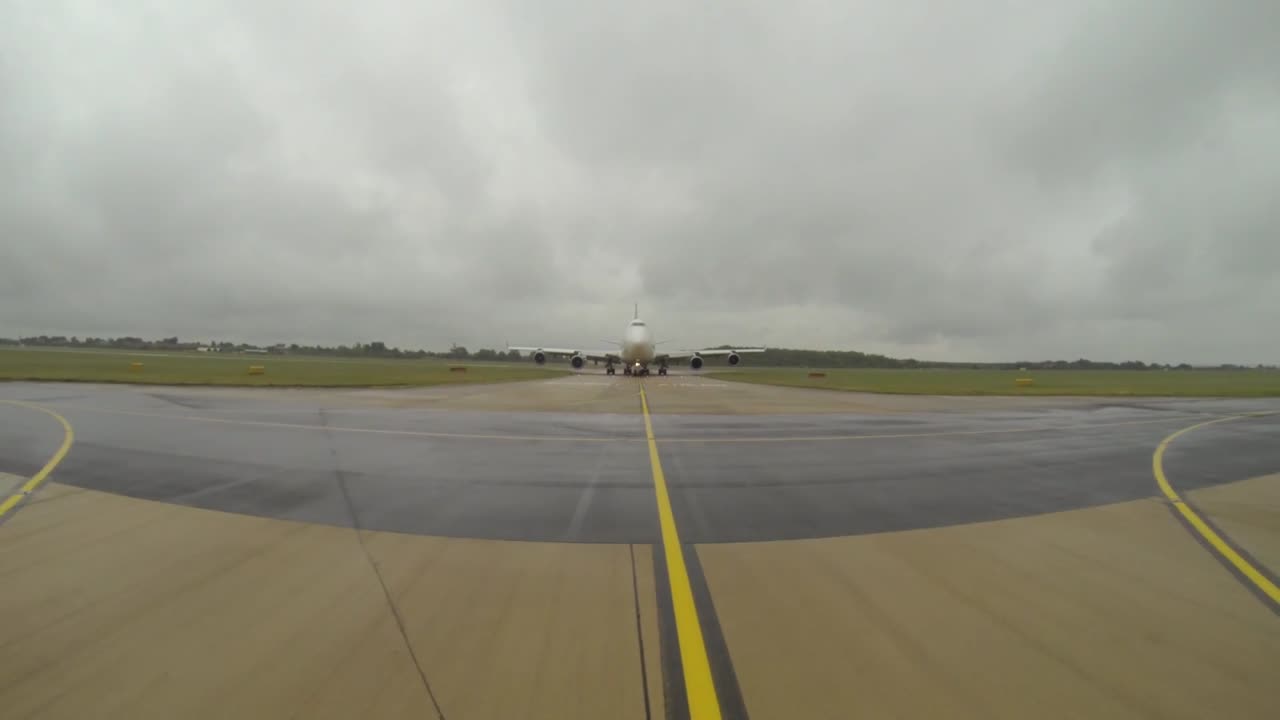 A vehicle drives in front of a large aircraft to give it guidance on where to go and where to park.