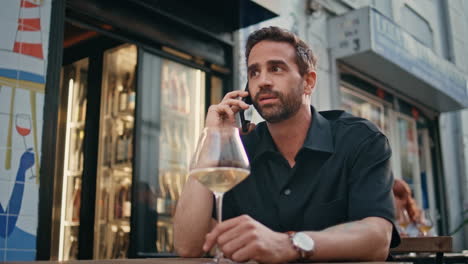 macho calling mobile phone in street bar close up. man holding wine glass