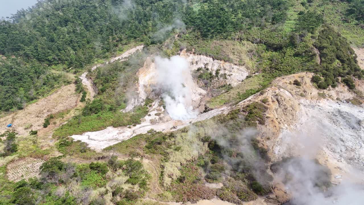 Drone footage showing a sulfur vent emitting white smoke in a mountainous geothermal landscape