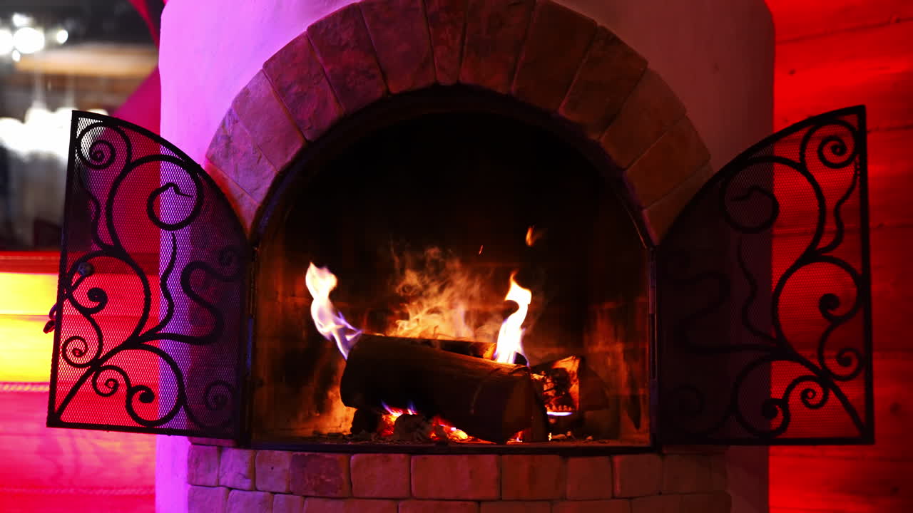 Wooden logs burning in fireplace. Beautiful brick fireplace with modern design. Cosiness and comfort at home in winter.