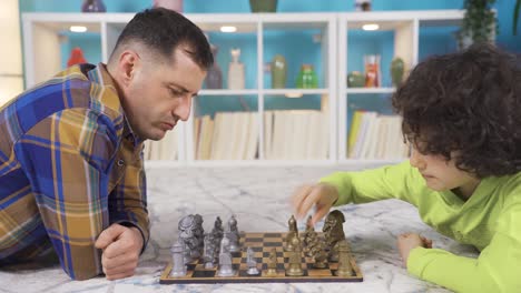 father plays chess with his smart son at home. playing games that develop intelligence and thinking.