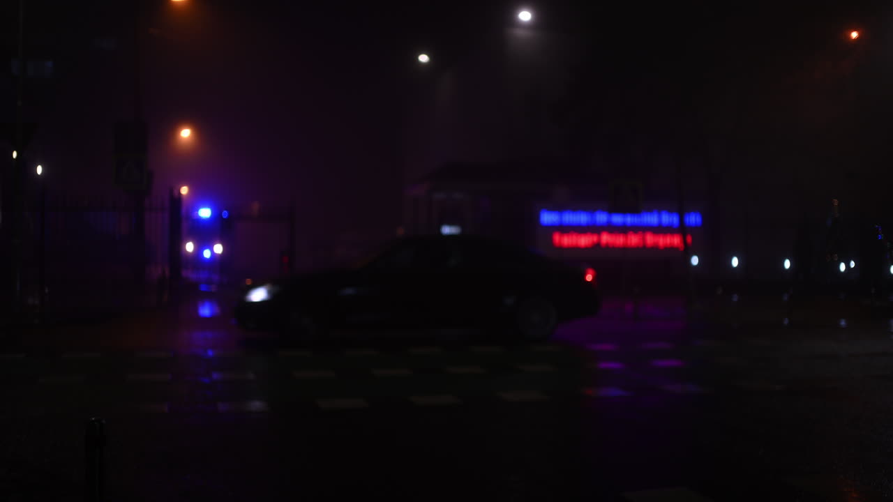 Out of focus view of a foggy urban intersection at night with neon signage and streetlights glowing through mist