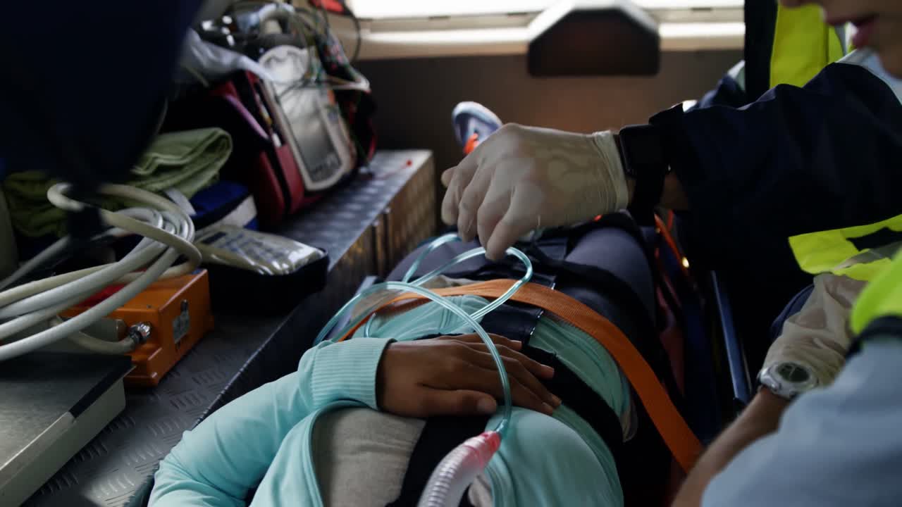 응급 의료 기술자가 부상당한 여성을 차로 데려간다.