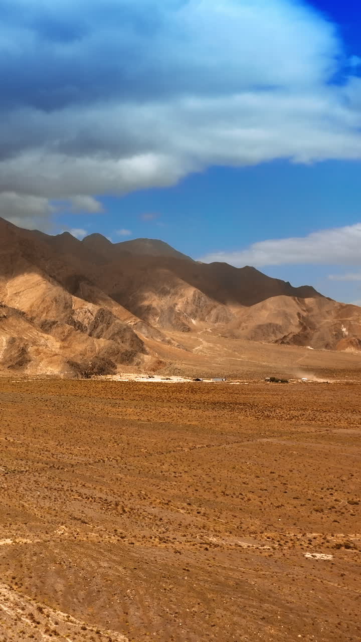 Rising above the deserted landscape surrounded by bare mountains. Dry hot scenery of Nevada. Dramatic cloudscape hanging over the mount. Vertical video