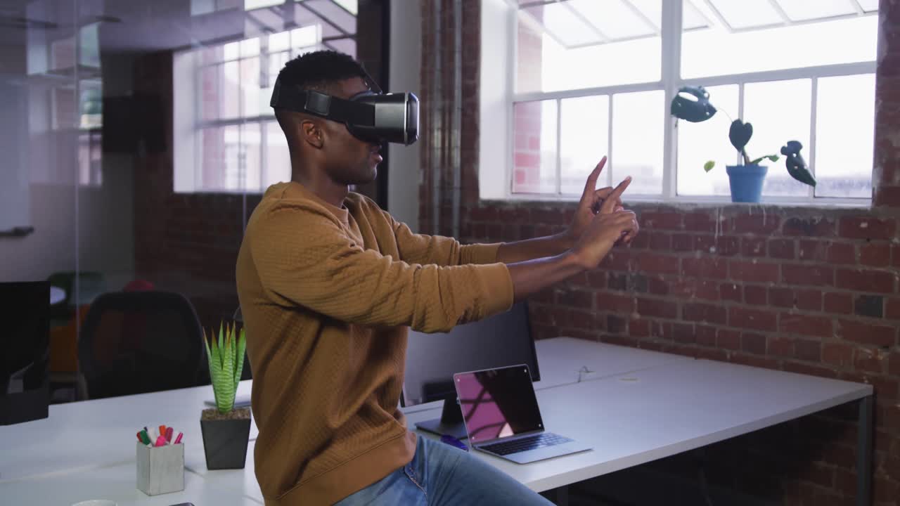 African american businessman sitting on desk using vr headset and gesturing