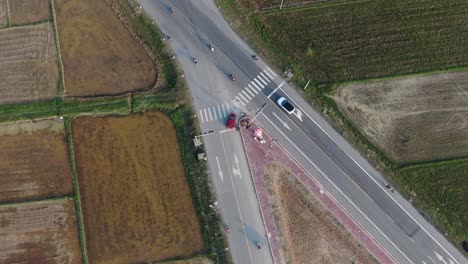 Vista-Giratoria-De-Arriba-Hacia-Abajo-De-Los-Vehículos-Que-Conducen-A-Través-De-La-Intersección-Entre-La-Granja-De-Arrozales