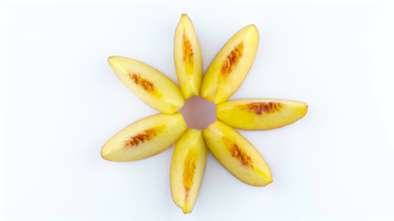 secciones de frutas de melocotón maduras. vista superior desde arriba de las rebanadas de melecotón que forman una forma de estrella. rotando en la mesa giratoria aislada en el fondo blanco. close up. macro.