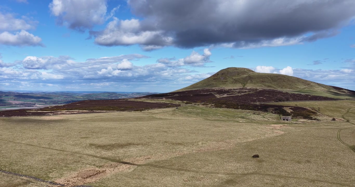 Panorerende luftfoto over et typisk bakkelandbrug med får i Fife, Skotland. Beliggende i Lomond Hills viser billedet East Lomond-bakken (Falkland Hill) i baggrunden.