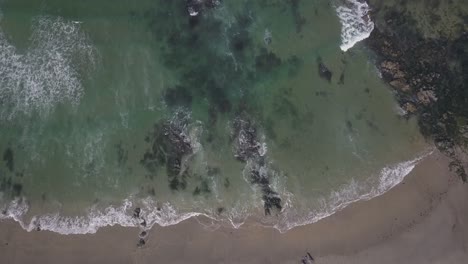 Kleine-Wellen,-Die-Die-Felsen-Am-Strand-Treffen