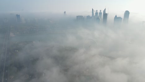 FOG-IN-UAE:-Aerial-view-of-Fog-over-Sharjah's-Khalid-Lake,-Sharjah-skyline-covered-in-the-winter-morning-fog,-United-Arab-Emirates,-4K-Drone-Footage