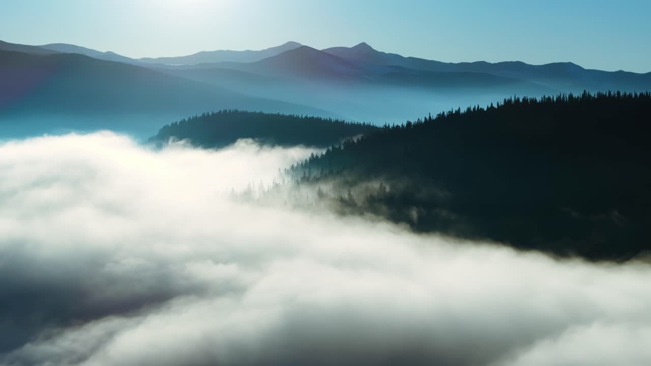 Juniper Pass mountain valley covered in mist and drifting clouds, ethereal morning aerial backdrop