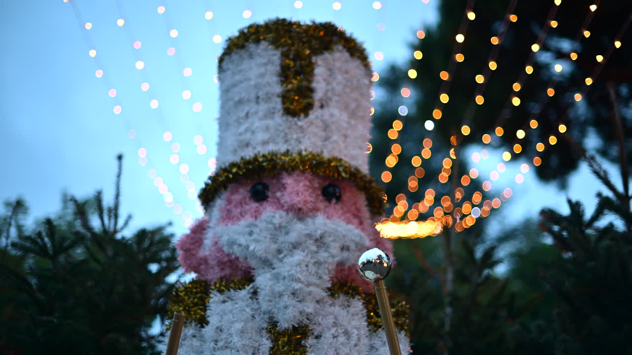 Decorative Christmas nutcracker soldier figure displayed outdoors with trees in the background
