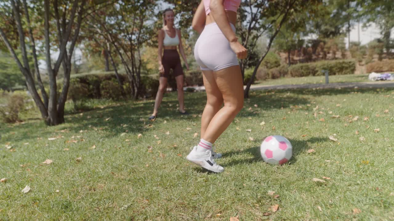Two women playing soccer in the park