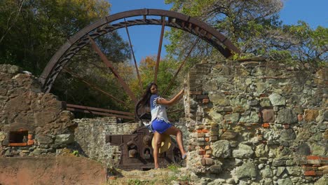 a model standing at an old waterwheel from a sugar cane estate