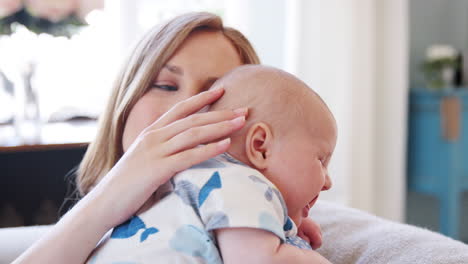 Toma-En-Cámara-Lenta-De-Una-Madre-Sentada-En-Un-Sofá-En-Casa-Abrazando-A-Un-Hijo-Cansado