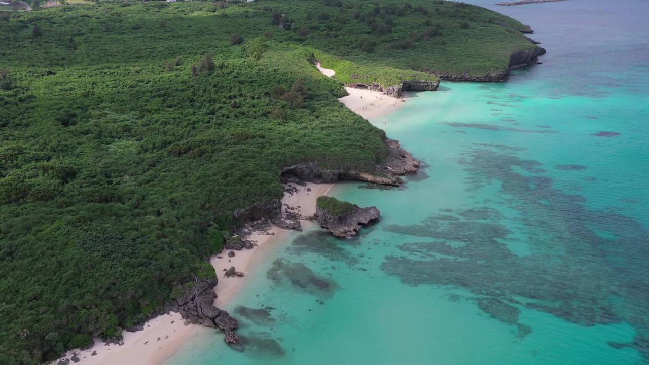 Riprese aeree orizzontali che si allontanano all'indietro con un'inclinazione verso il basso sopra la spiaggia di Sunayama e la spiaggia di Nikawatori, Miyakojima, Okinawa, Giappone.