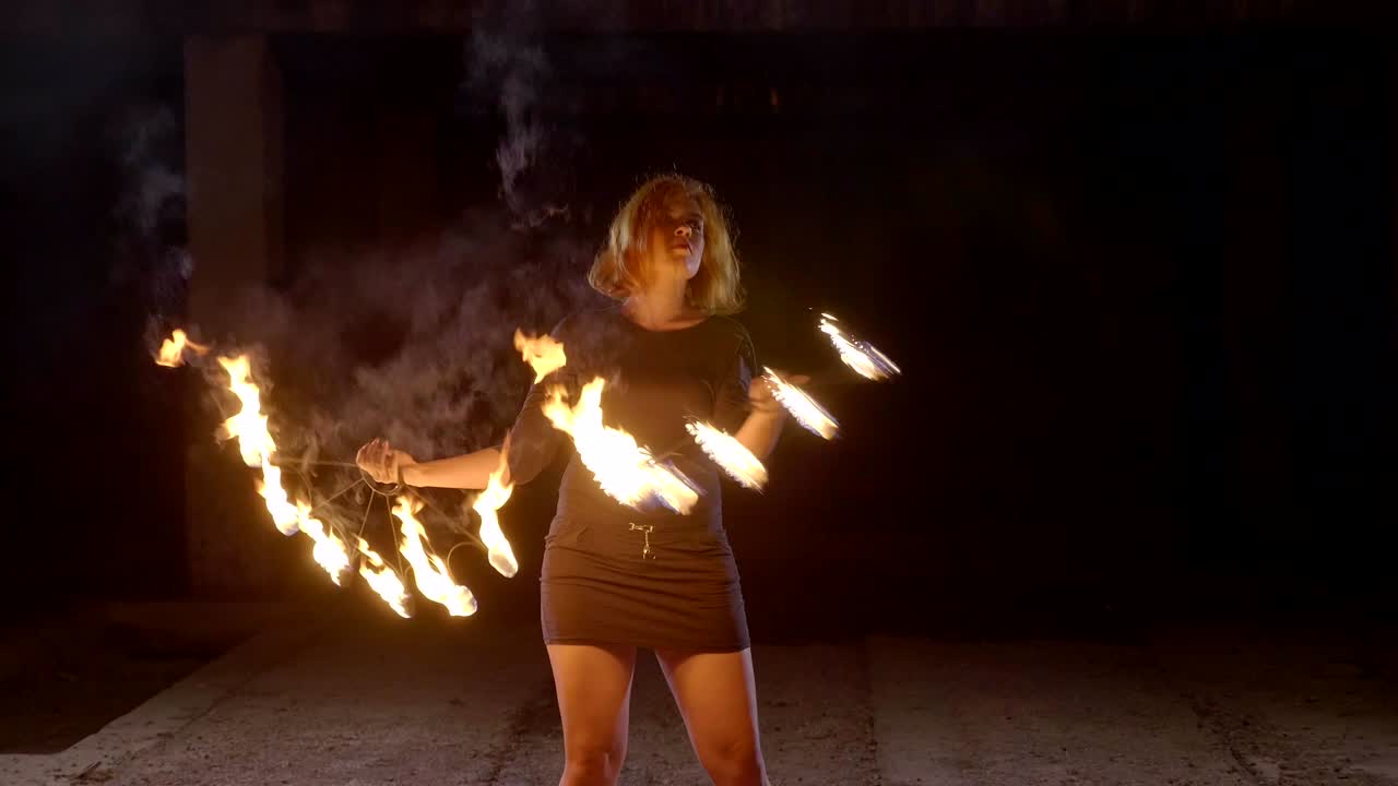 una artista de yong hace un espectáculo de fuego en la oscuridad a cámara lenta.