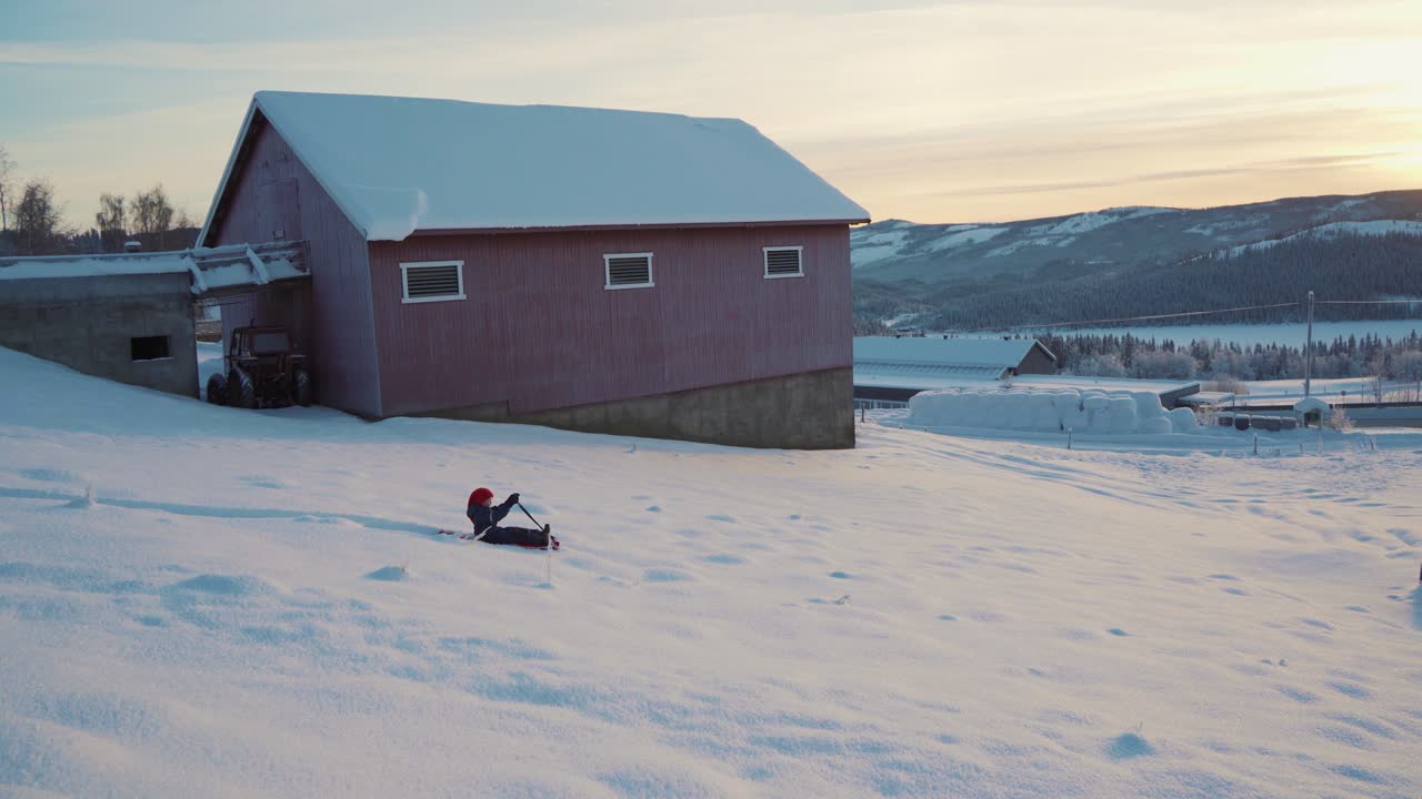 En ung gutt som møter litt problemer på aketuren sin i det frostklare og snødekte landskapet i Norge i juletiden.