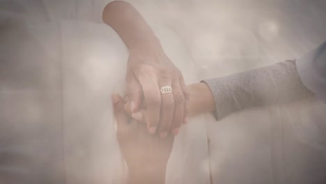 animation of glowing light over female nurse holding senior woman's hands