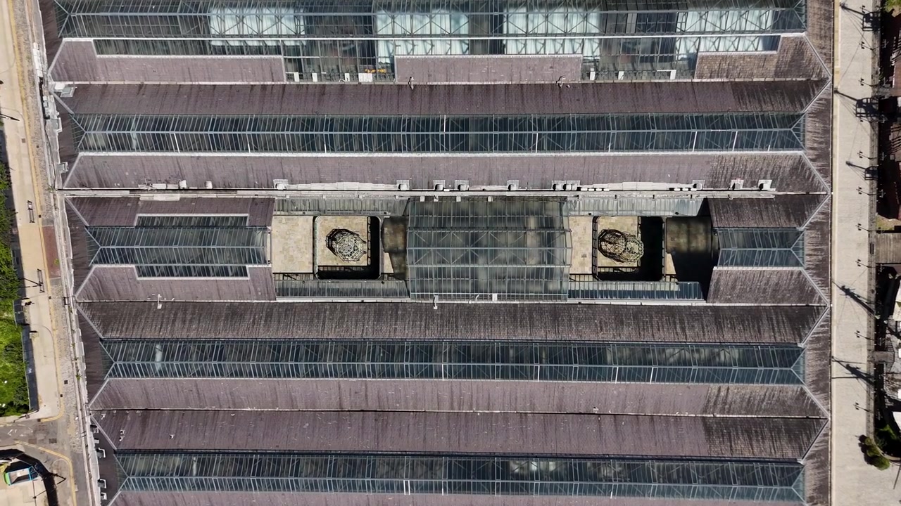 Top down view of the glazed roof of a historic brick warehouse showing rows of skylights and ventilation shafts