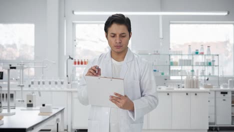 cheerful indian scientist writing observations