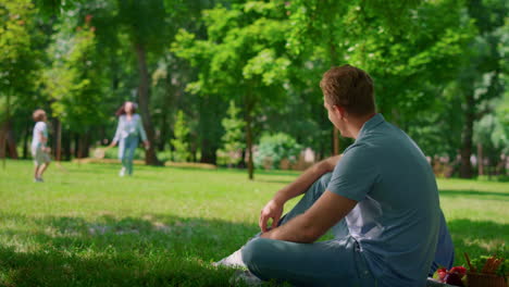 smiling father sitting on playing family background. active leisure on nature.