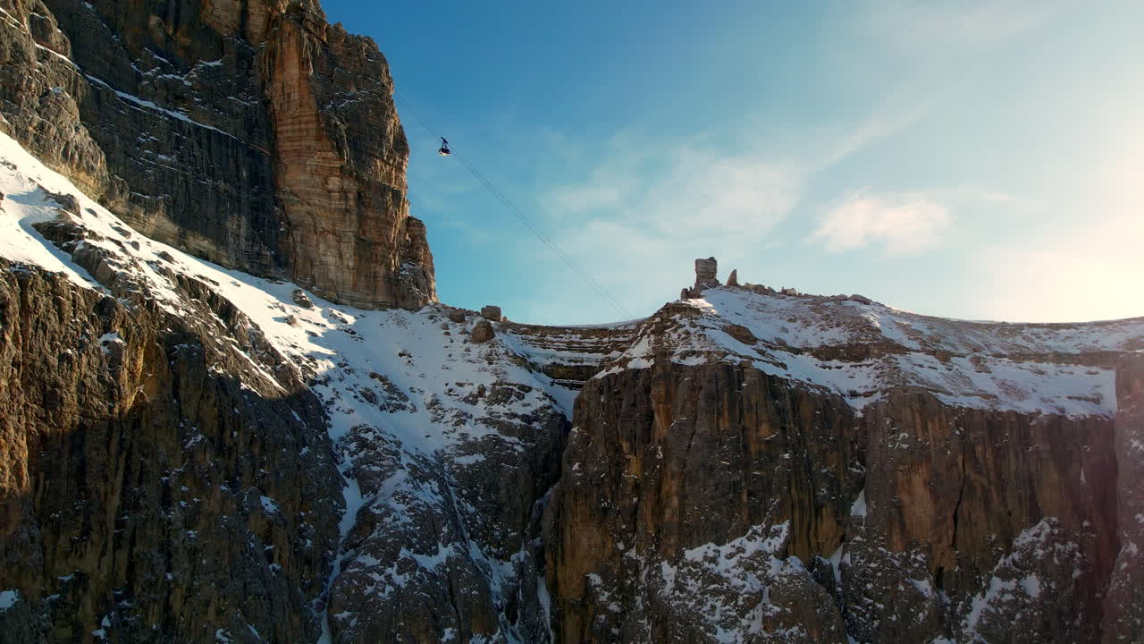 un teleférico se desliza a través de una cordillera cubierta de nieve bajo un cielo azul claro, mostrando la belleza escarpada de la naturaleza