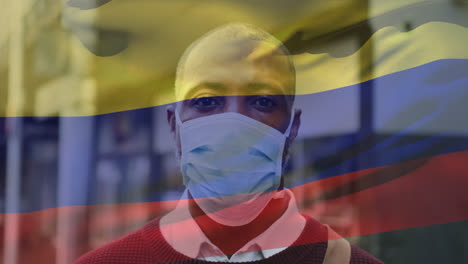 animation of waving colombia flag over portrait of african american man wearing face mask on street