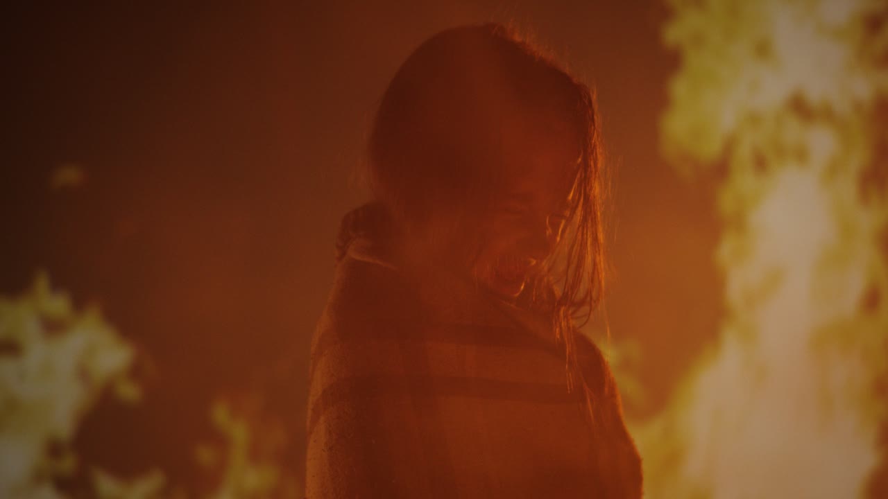 Person in blanket smiling by firelight