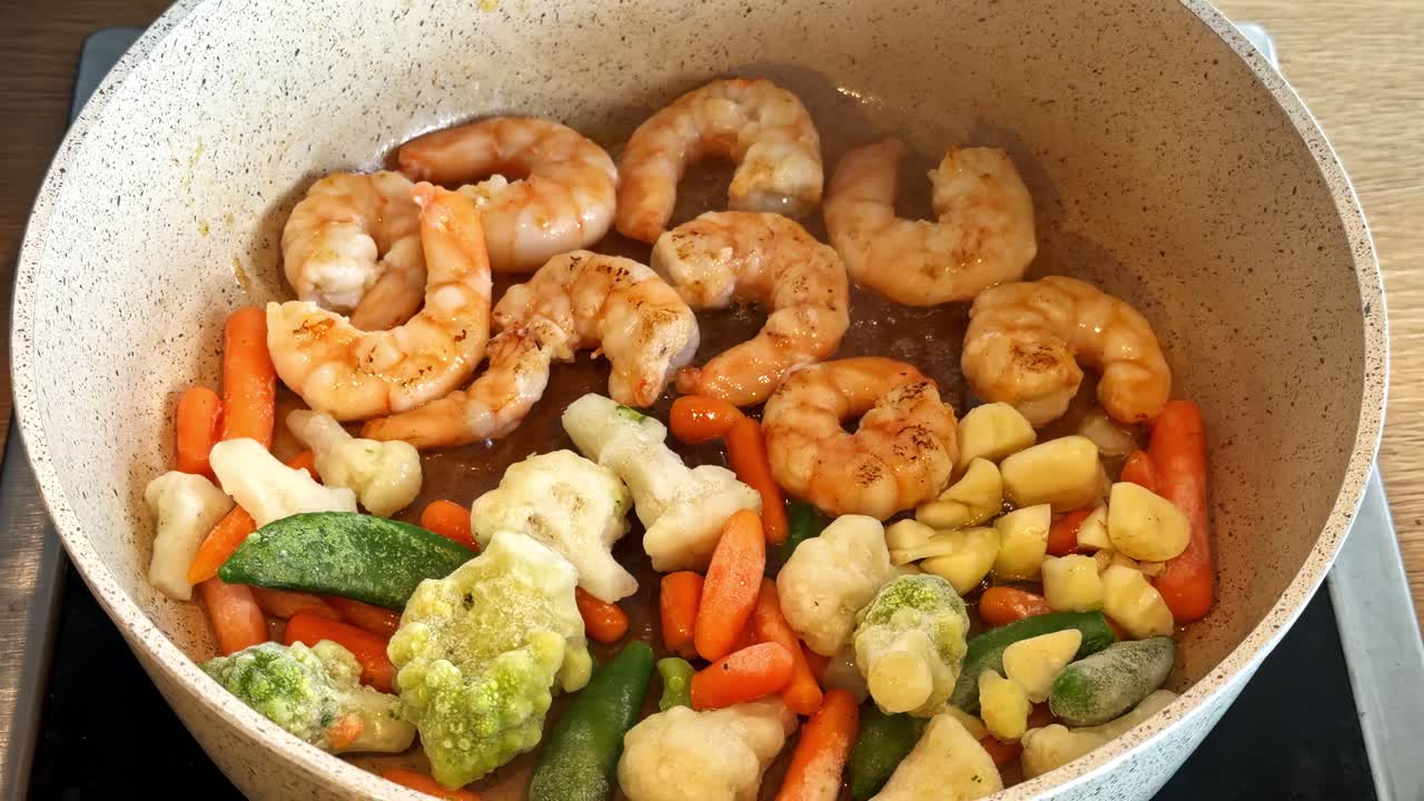 Shrimp and mixed frozen vegetables cooking in a pan, close-up