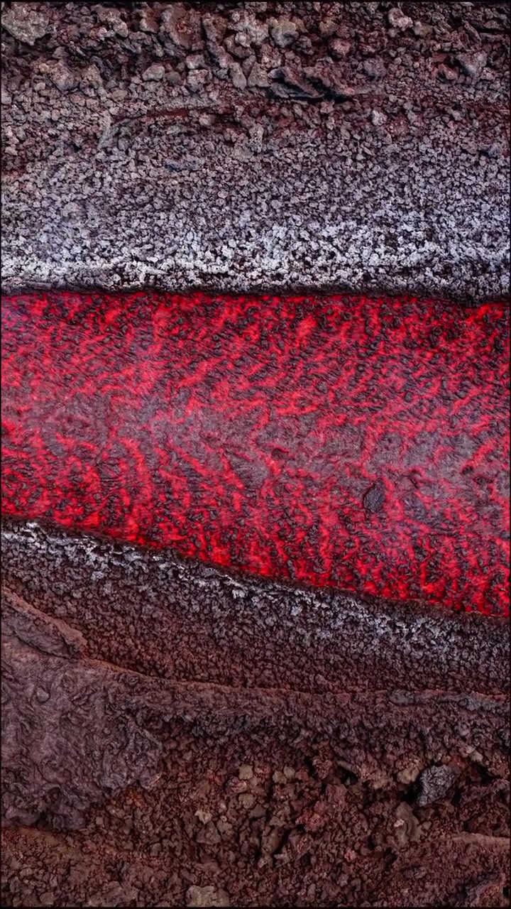 Lava fusa scorre attraverso roccia vulcanica scura in una vista verticale dall'alto di un vulcano