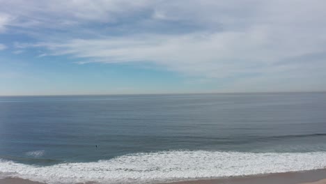 wide aerial shot flying over santa monica beach towards the pacific ocean