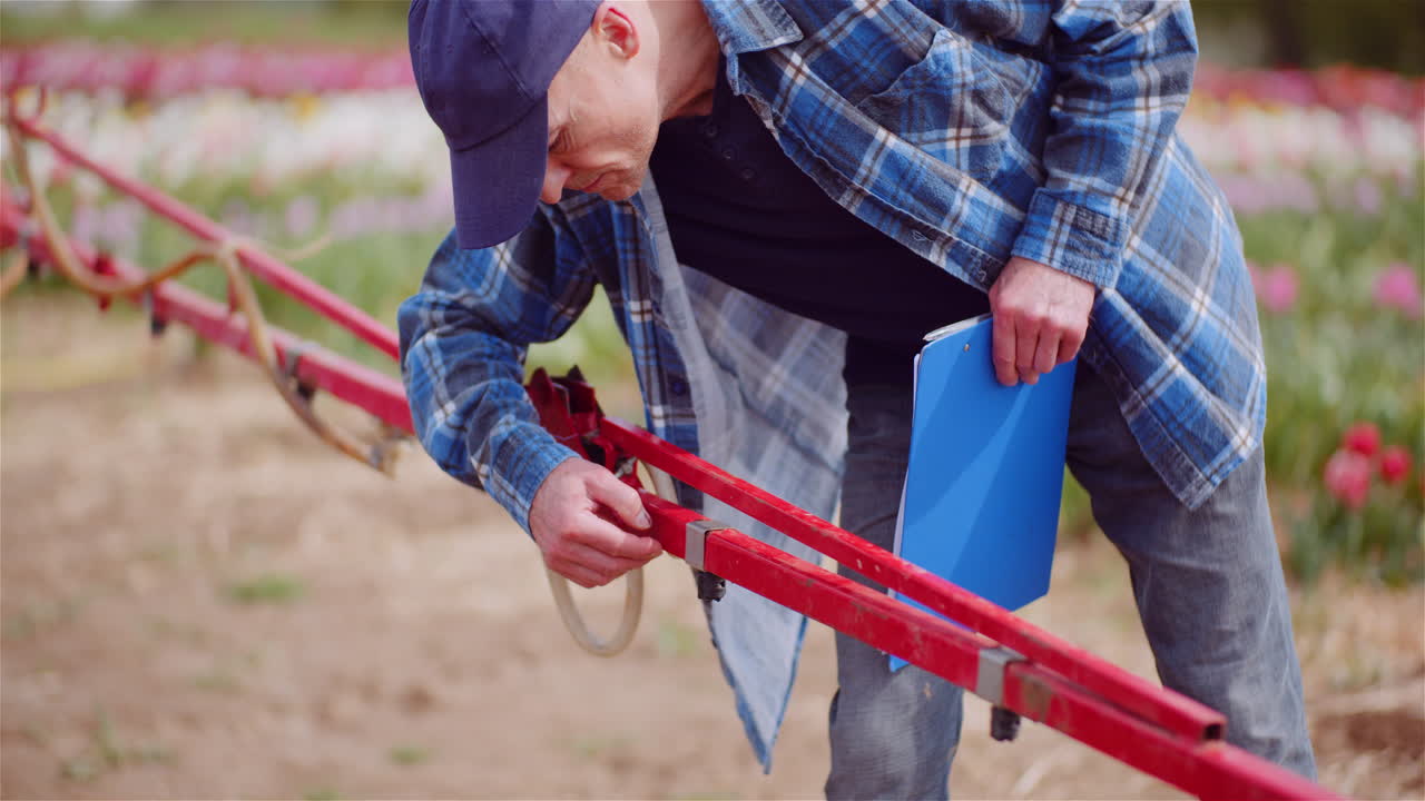 Farmer Inspecting Agricultural Sprayer Equipment in a Field