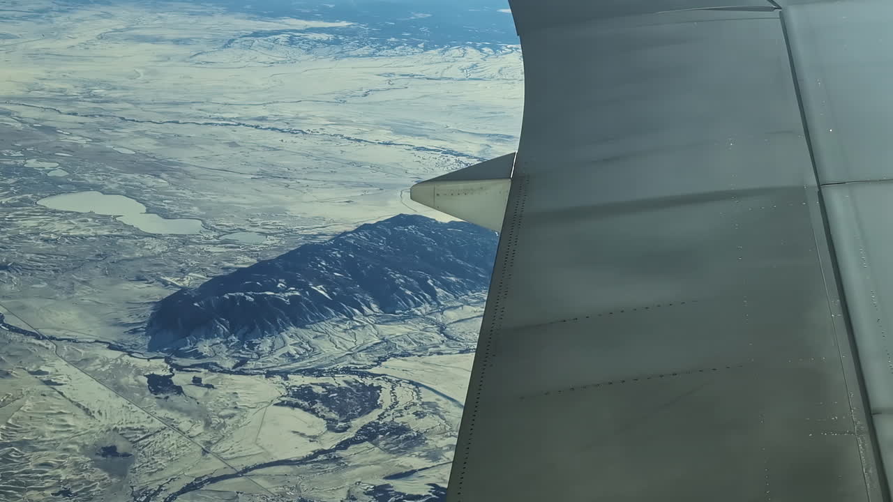 Volando sopra alte montagne coperte di neve, paesaggio con ala dell'aereo nell'inquadratura