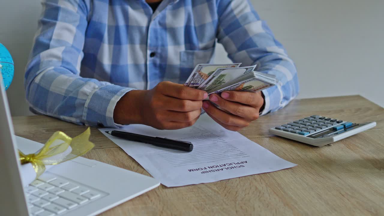 Estudiante rellena formulario de beca y prepara dinero para el pago